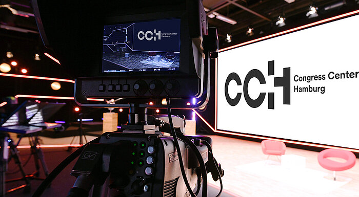 Hybride Veranstaltungen im CCH Blick auf eine Bühne, CCH Logo auf der Leinwand